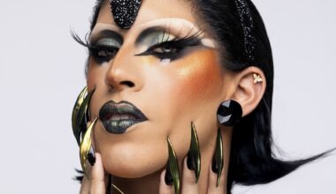 headshot of a drag performer in heavy makeup with dark eyeshadow and lips with pointy nails