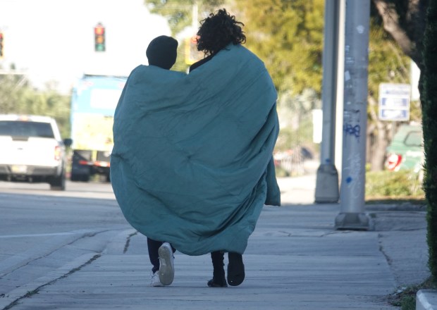 Pedestrians on Atlantic Boulevard in Pompano Beach share a blanket, Monday, Feb. 2, 2026. (Joe Cavaretta/South Florida Sun Sentinel)