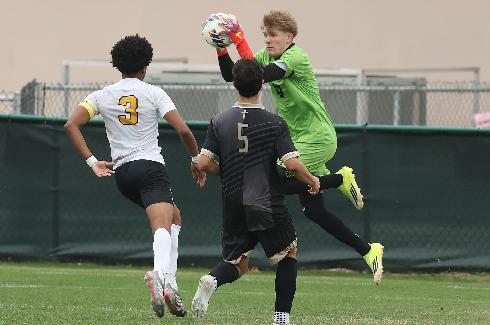 Bishop Moore Catholic High School goalkeeper Colin Norton (top) leaps...