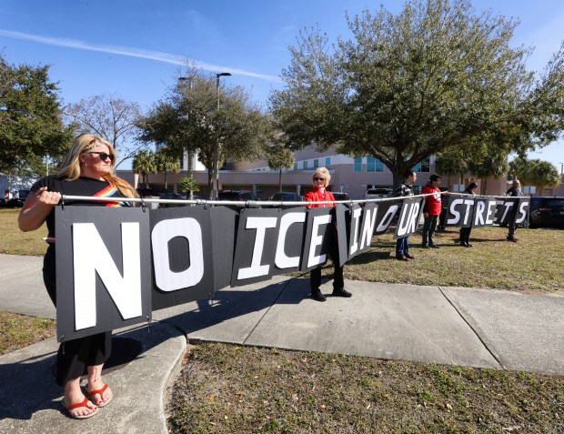 Candy Powell, left, helps hold a "No Ice in Our Streets" sign at an anti-ICE rally in front of the Orange County Jail, Friday, Jan. 30, 2026. Hosted by the Immigrants Are Welcome Here Coalition, dozens of protesters held signs along John Young Parkway to raise awareness for the ICE detainees held at the jail in Orlando and to announce an online petition drive. (Joe Burbank/Orlando Sentinel)