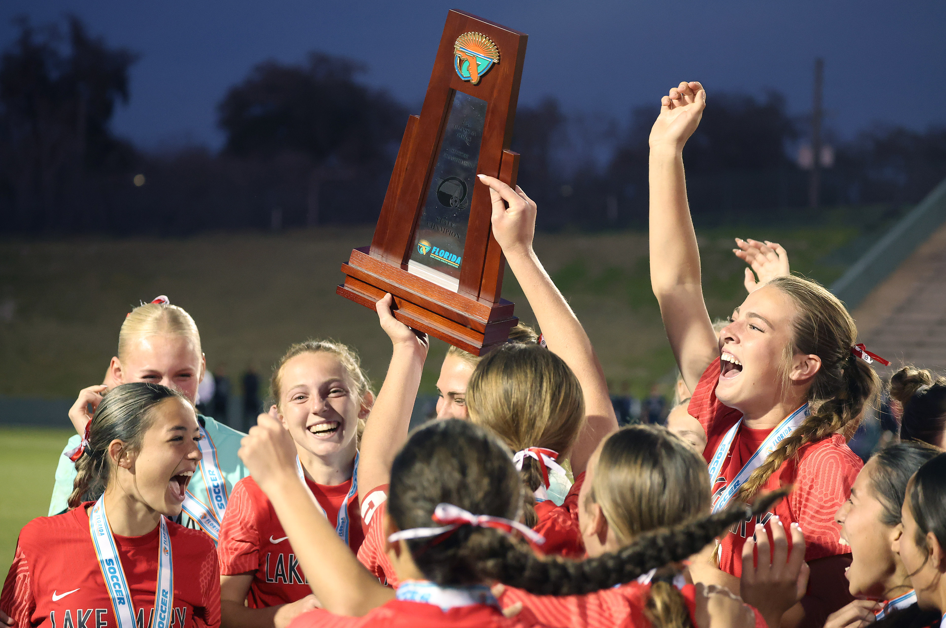 Lake Mary High girls soccer players celebrate with the trophy...
