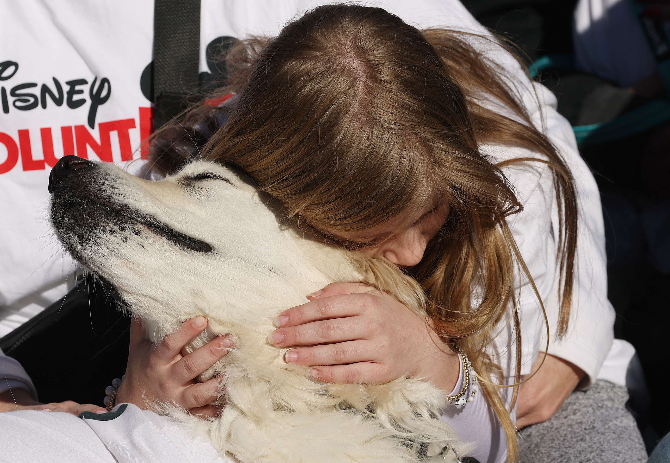 A young girl hugs her dog during the Paws in...