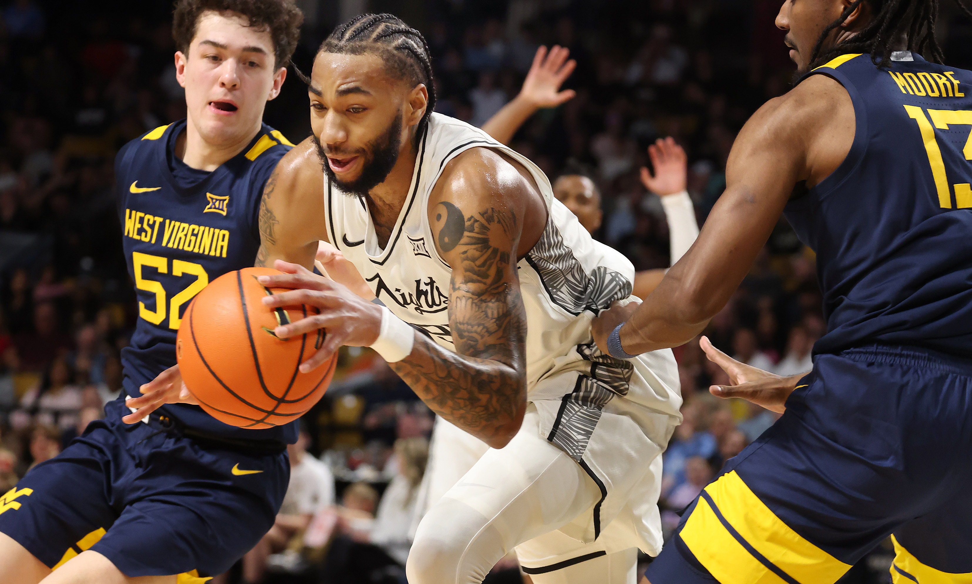 UCF forward Jordan Burks (middle) powers through West Virginia defenders...