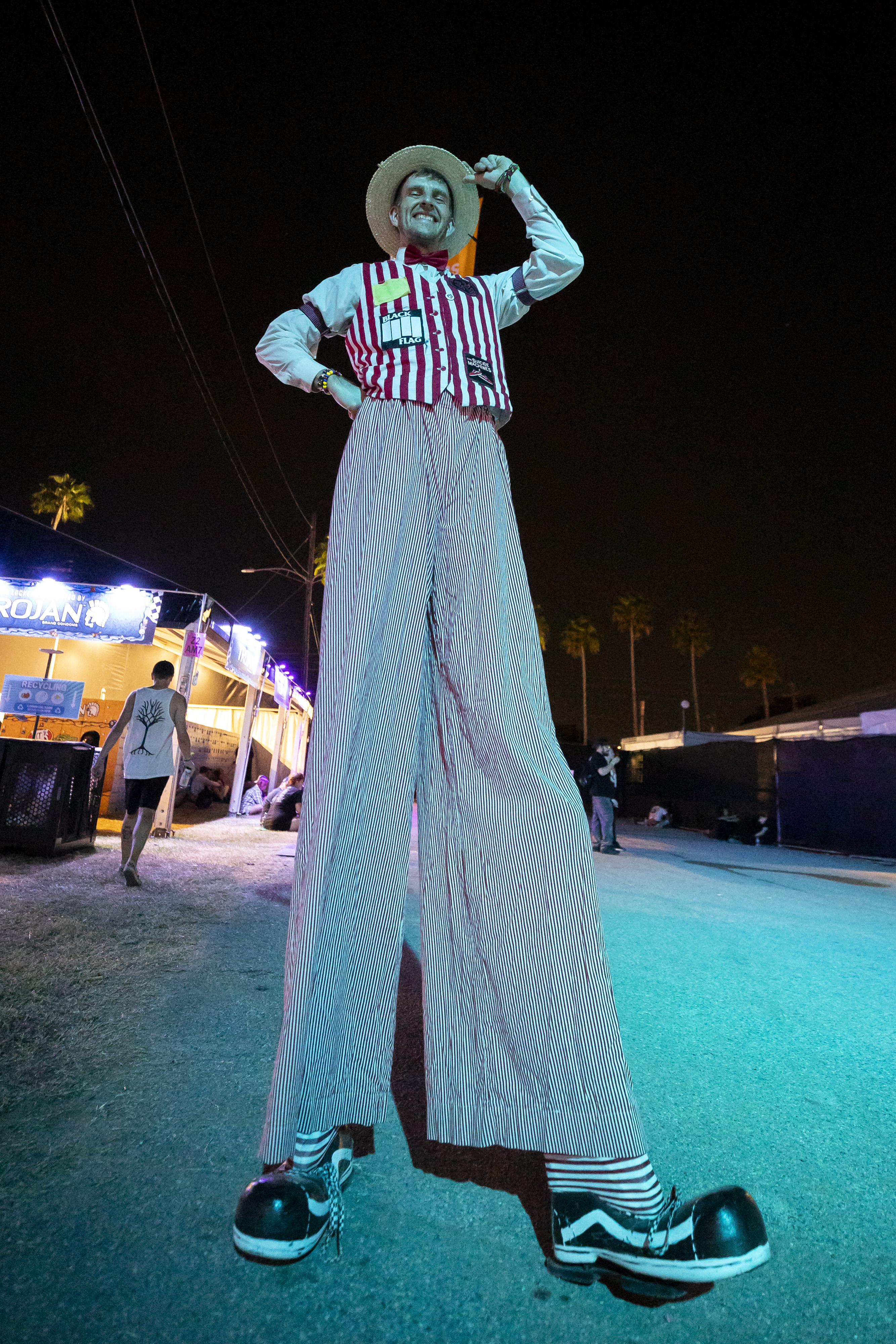 A performer on stilts is dressed up like a circus...