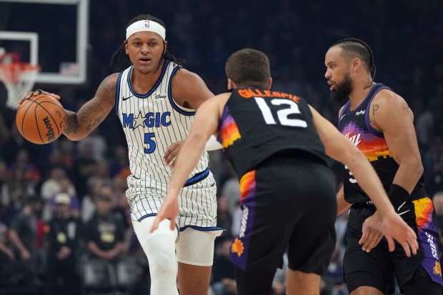 Orlando Magic forward Paolo Banchero shields the ball from Phoenix Suns forward Dillon Brooks and guard Collin Gillespie (12) during the first half of an NBA basketball game, Saturday, Feb. 21, 2026, in Phoenix. (AP Photo/Rick Scuteri)