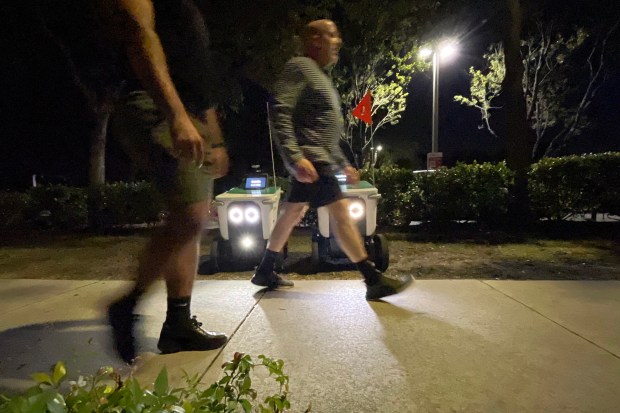 Pedestrians pass robot delivery vehicles staged along on Wilton Drive in Wilton Manors on Friday, Feb. 7, 2026. (Amy Beth Bennett / South Florida Sun Sentinel)