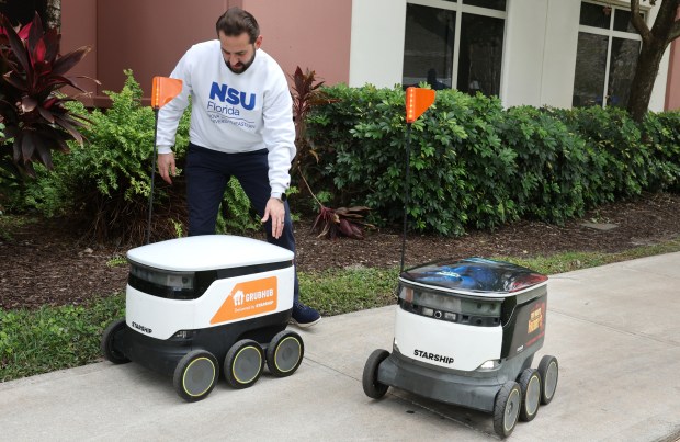 Mike Alkurdi, resident district manager at Nova Southeastern University in Davie, puts an autonomous robot back on track after it got stuck while delivering food on campus, Tuesday, Feb. 3, 2026. (Carline Jean/South Florida Sun Sentinel)