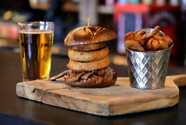 The smoked brisket sandwich with onion rings at the Hen and the Hog Smokehouse Cantina in Pompano Beach on Saturday, Aug. 16, 2025. (Mike Stocker/South Florida Sun Sentinel)