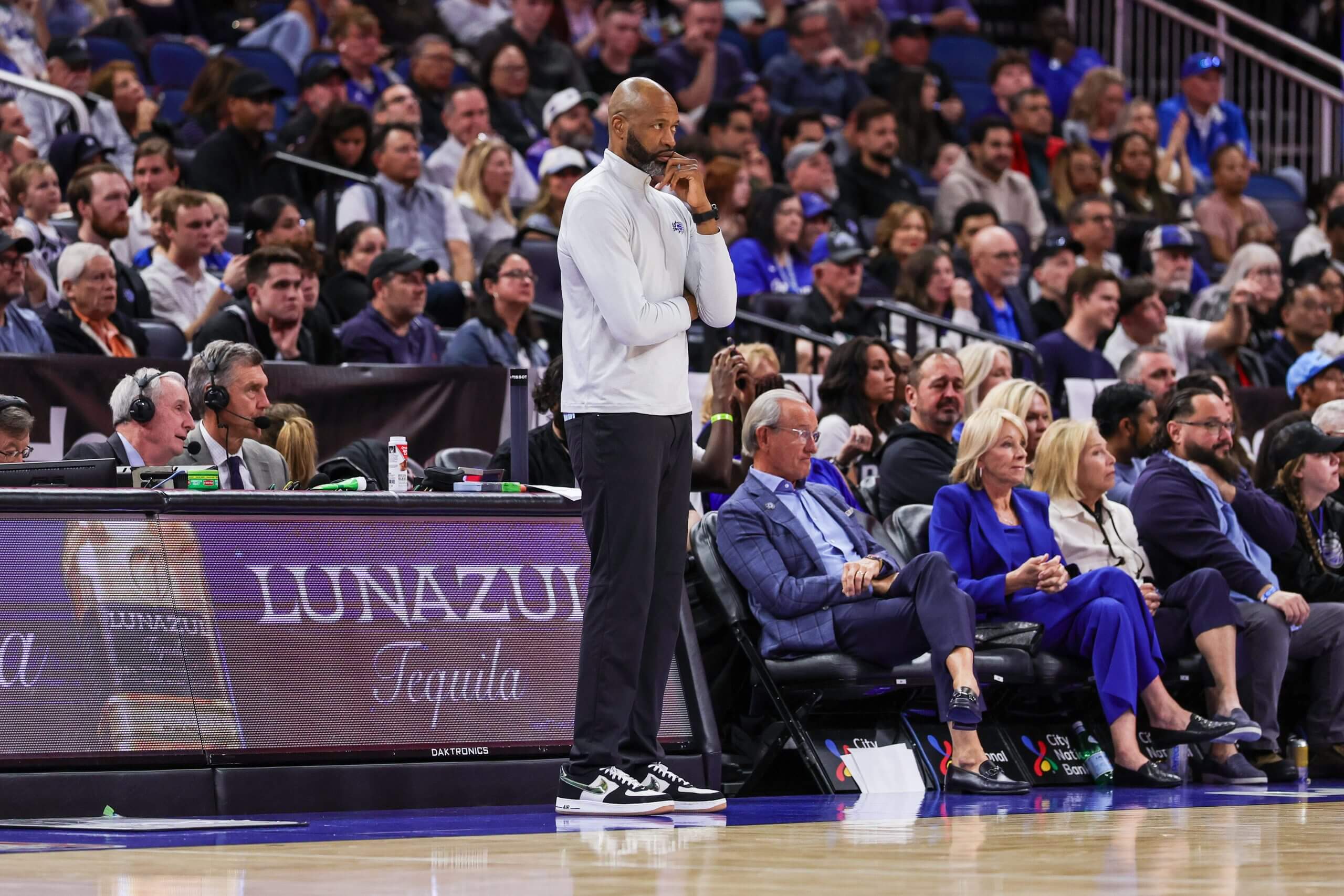 Jamahl Mosley stands on the sideline, with his right arm crossed beneath his rib cage and his left hand at his chin.
