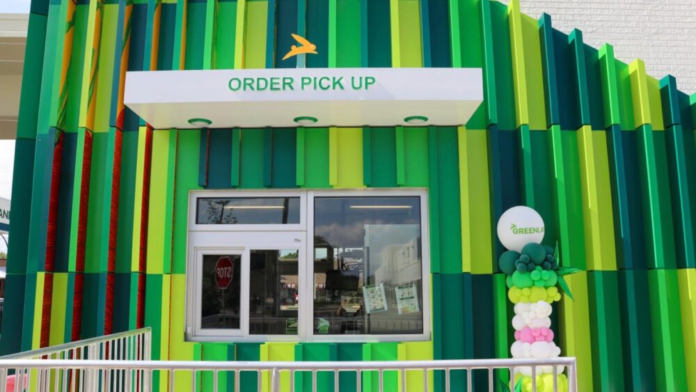 Greenlane order pickup window framed by the restaurant’s green vertical panel facade.