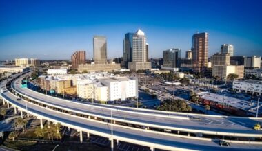 Aerial view of the Lee Roy Selmon Expressway curving toward downtown Tampa with skyline in background.