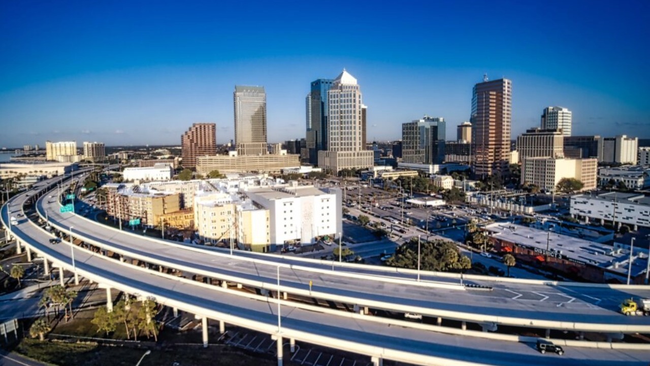 Aerial view of the Lee Roy Selmon Expressway curving toward downtown Tampa with skyline in background.