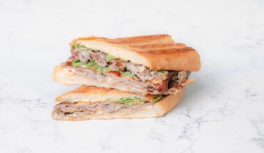 Bern’s Steak House and La Segunda Bakery steak sandwich, sliced in half on a white marble surface.
