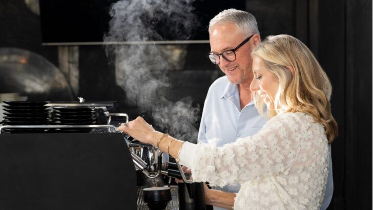 Susan Ward prepares coffee at an espresso machine as Dave Ward looks on inside a Buddy Brew Coffee space.