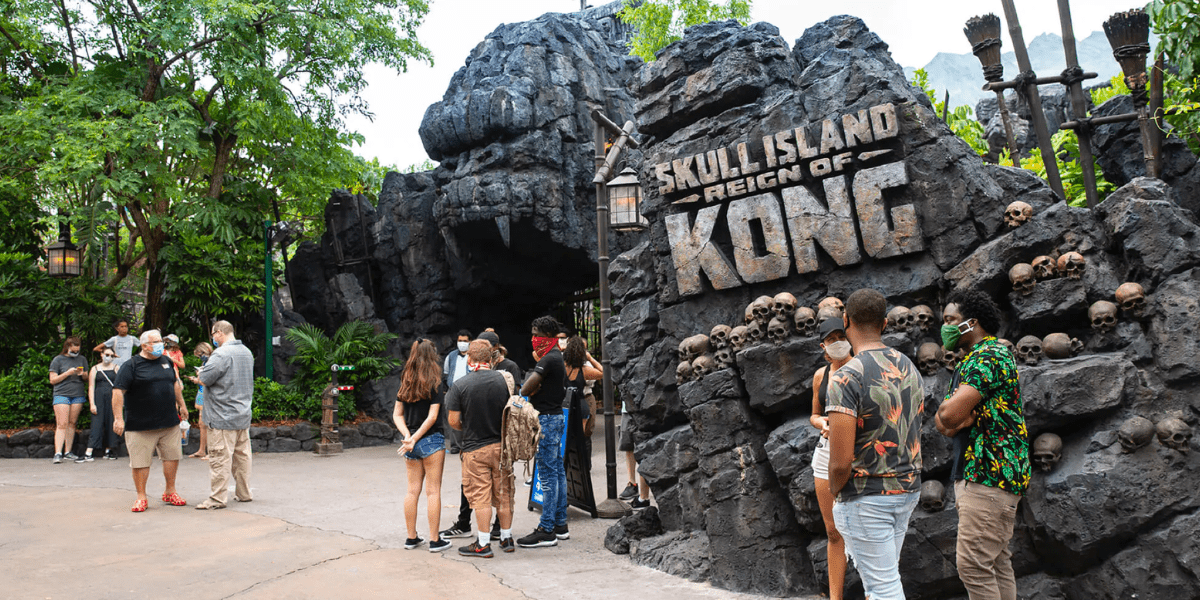 Guests stand outside the entrance for Skull Island: Reign of Kong, which is made of rocks.