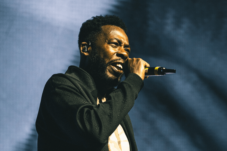 GZA of Wu-Tang Clan performing live on stage at Amalie Arena in Tampa during a June 2025 concert.