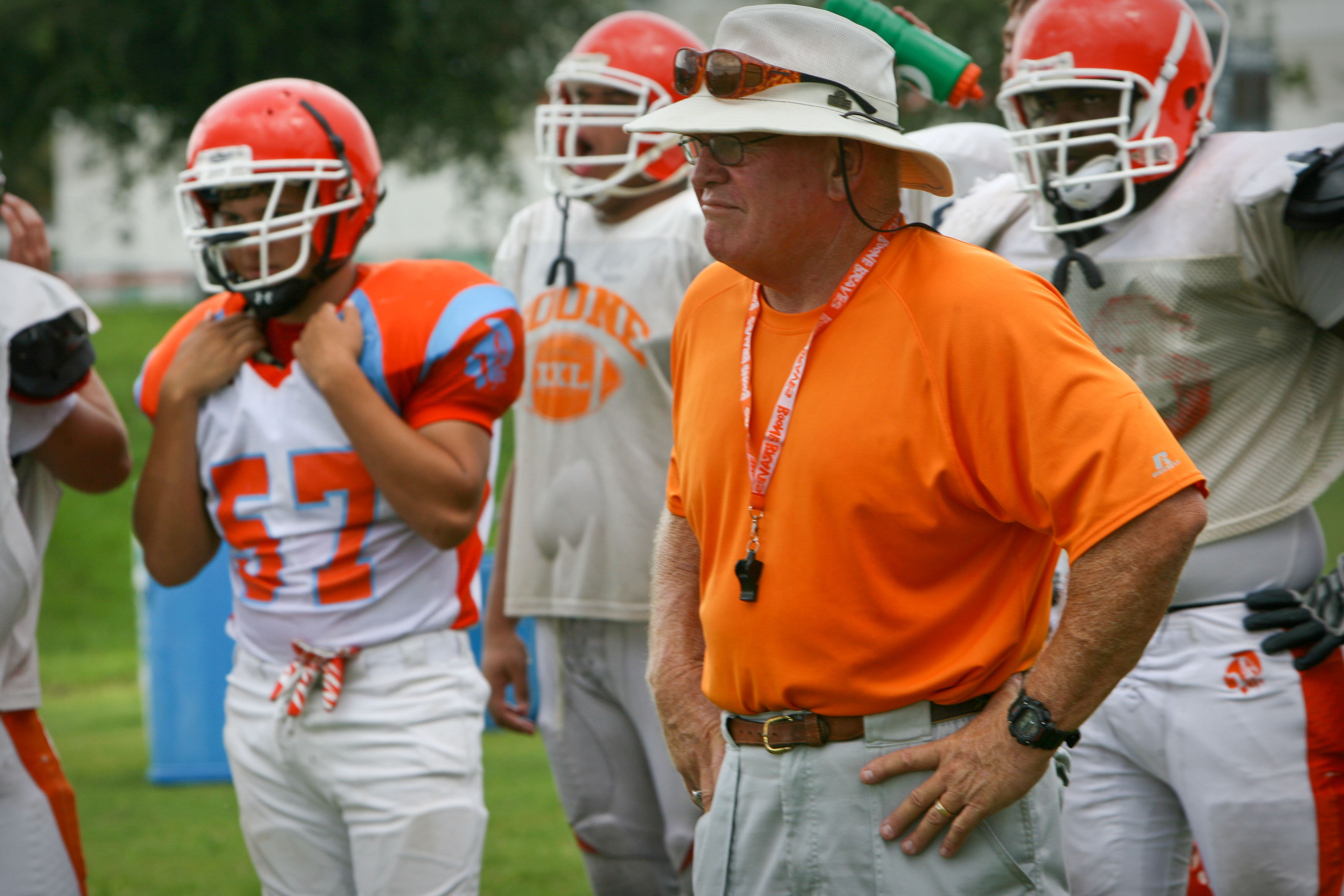 Coach Phil Ziglar watches players run drills during football practice...