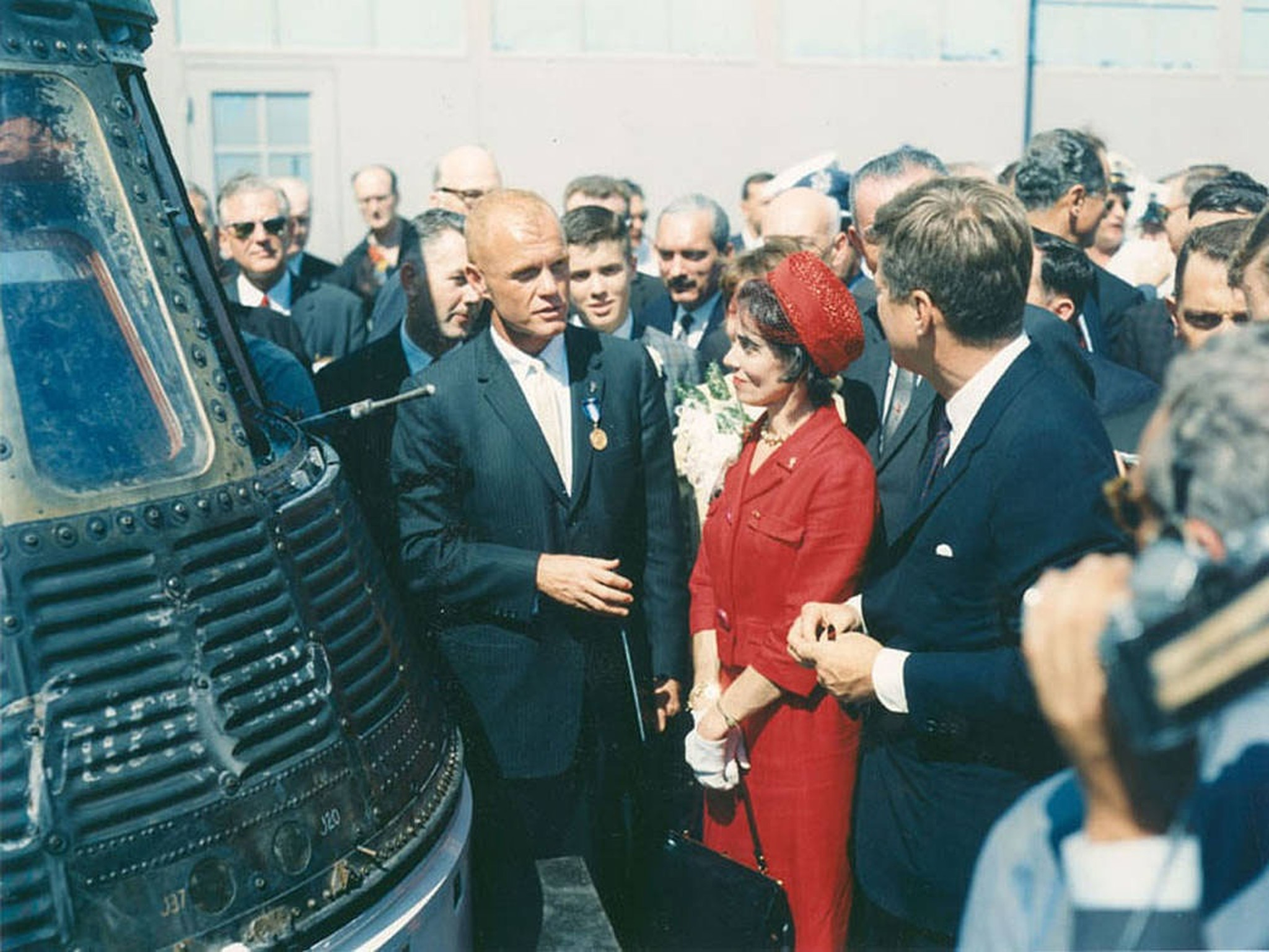 John Glenn, standing next to his Friendship 7 capsule in...