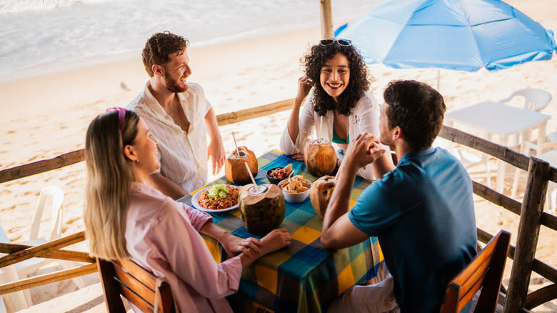 A group of four friends dining at a beachside restaurant