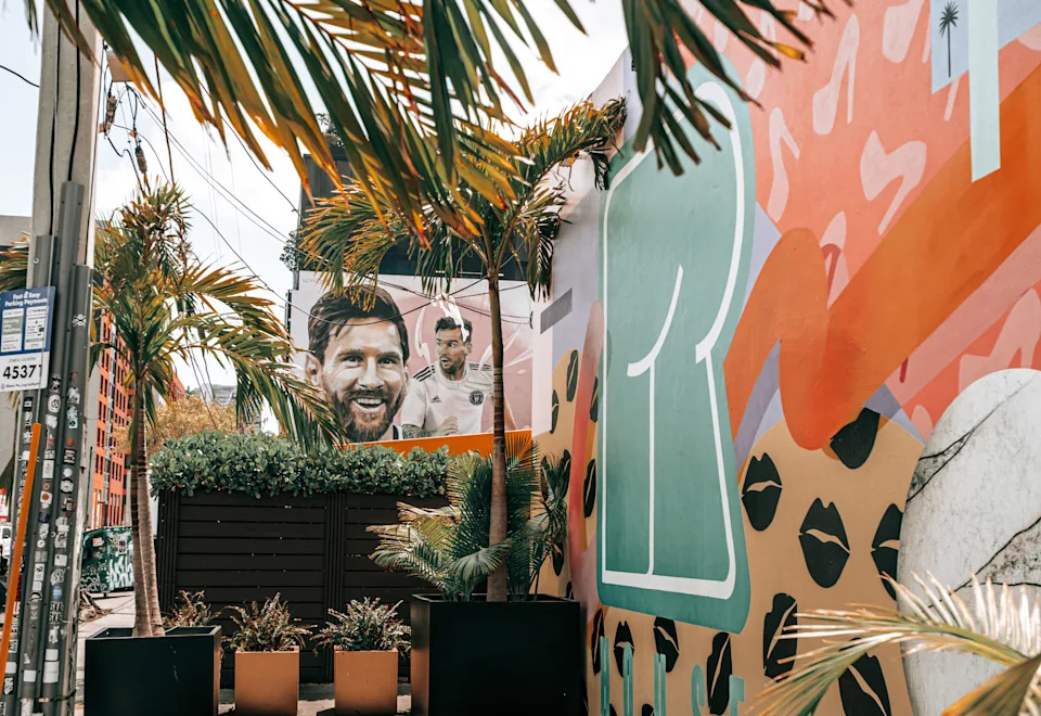 Miami, Florida, USA - April 16, 2025: A large, vibrant mural in Miami’s Wynwood district features soccer star Lionel Messi in an Inter Miami jersey, blending portraiture and dynamic action with a tropical backdrop of palm trees.