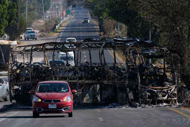 Vehicles drive past a charred bus the day after the Mexican army killed Jalisco New Generation Cartel leader Nemesio Oseguera Cervantes, known as "El Mencho," in Guadalajara, Mexico, Monday, February 23.