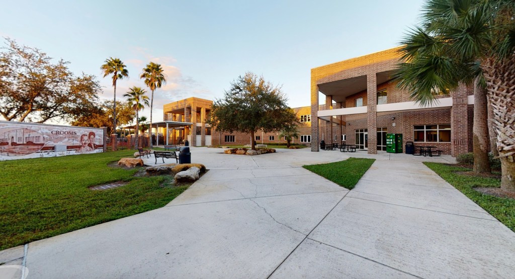 The campus of Crooms Academy of Information Technology in Sanford, Florida, featuring brick buildings, palm trees, and a mural.