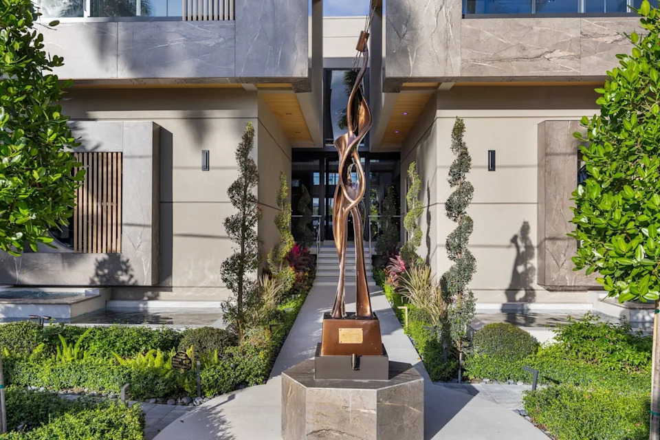 Symmetrical plants flank an eye-catching sculpture in front of the house.