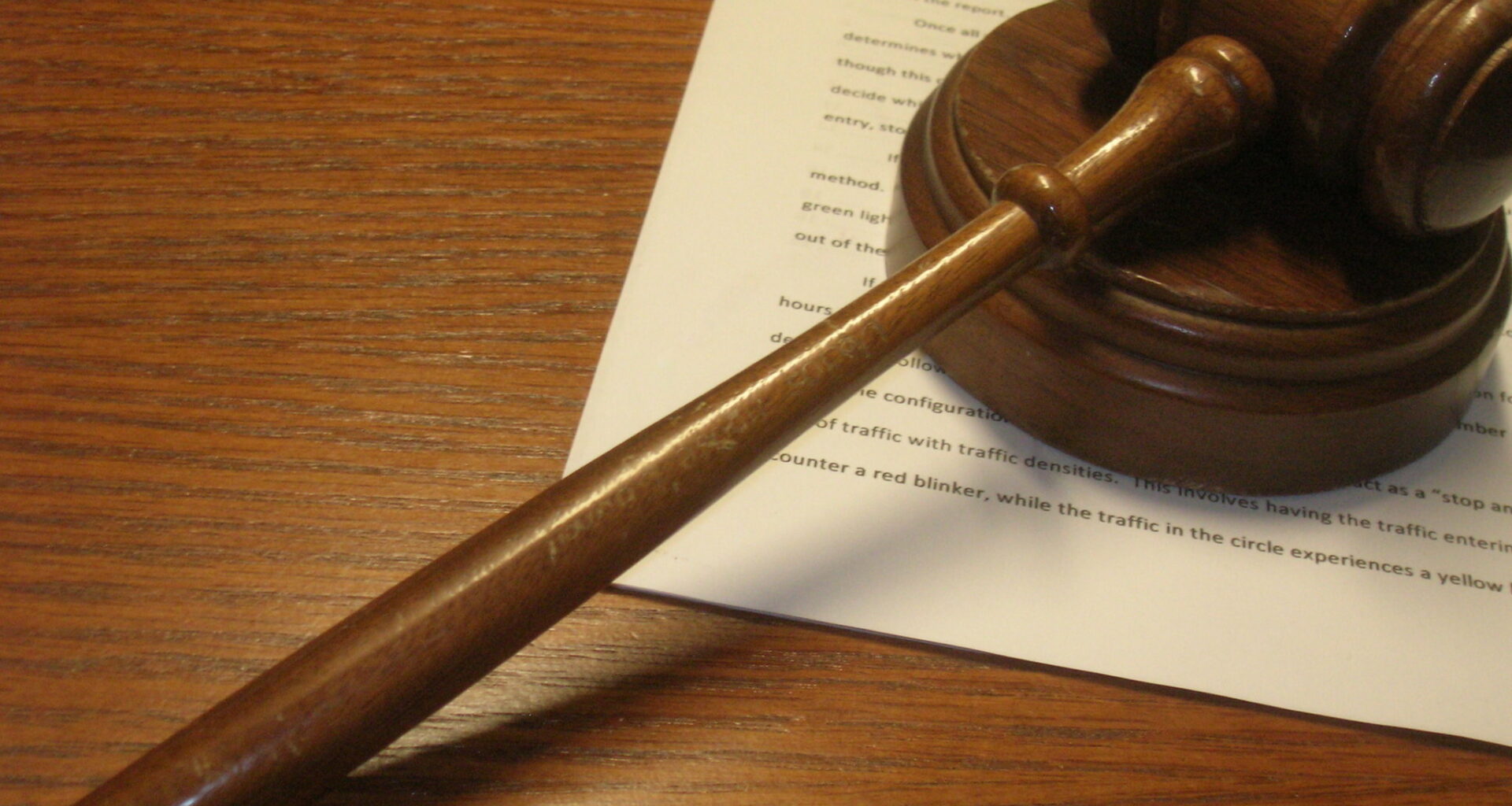 a wooden gavel on a wooden desk on top of some legal paperwork