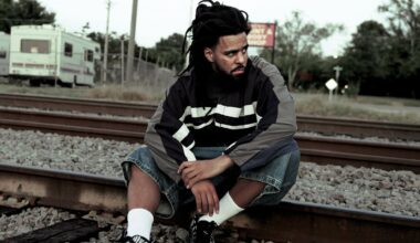 Rapper J. Cole sitting on a railroad track.