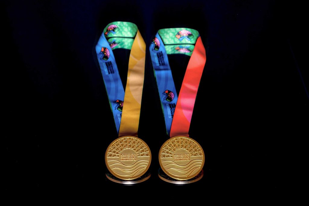 Two gold medals with multicolored ribbons displayed side by side against a black background, symbolizing athletic achievement or competition awards.