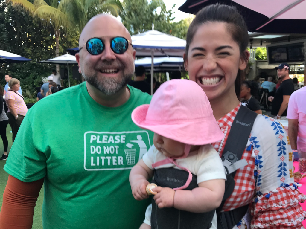 A man and a woman smiling while holding a baby