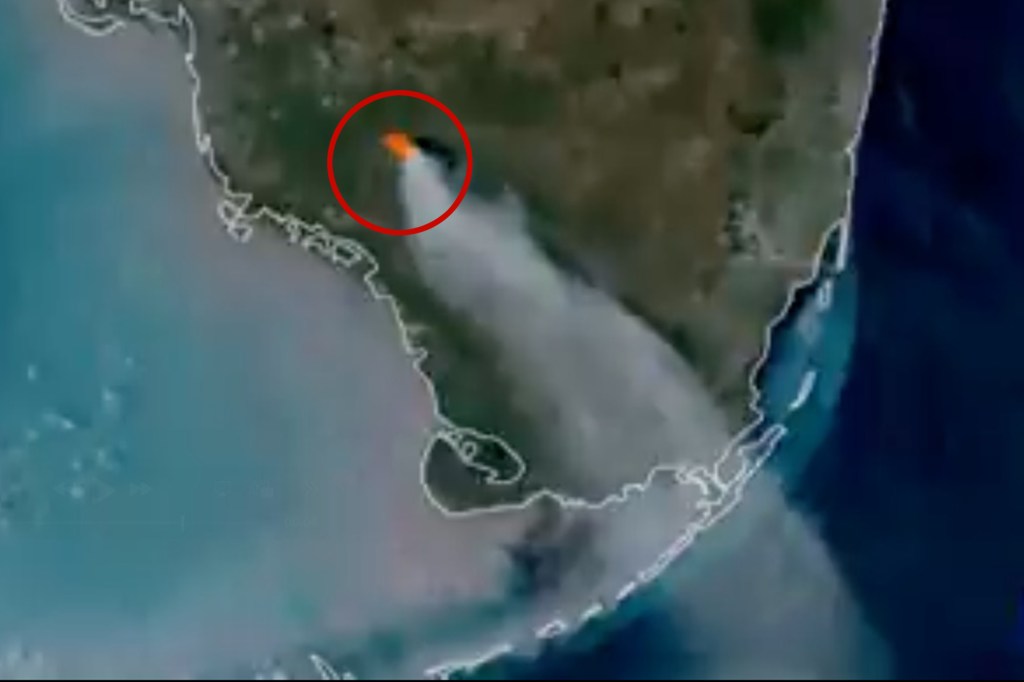 Satellite footage showing a wildfire in South Florida's Big Cypress National Preserve, with a plume of smoke spreading southeast.