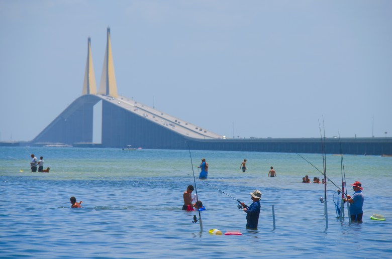 people fishing and swimming by the Sunshine Skyway Bridge