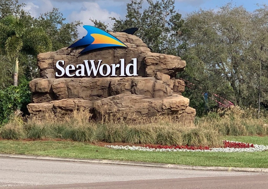 A sign at the entrance to SeaWorld Orlando featuring the park's logo on a rock formation.