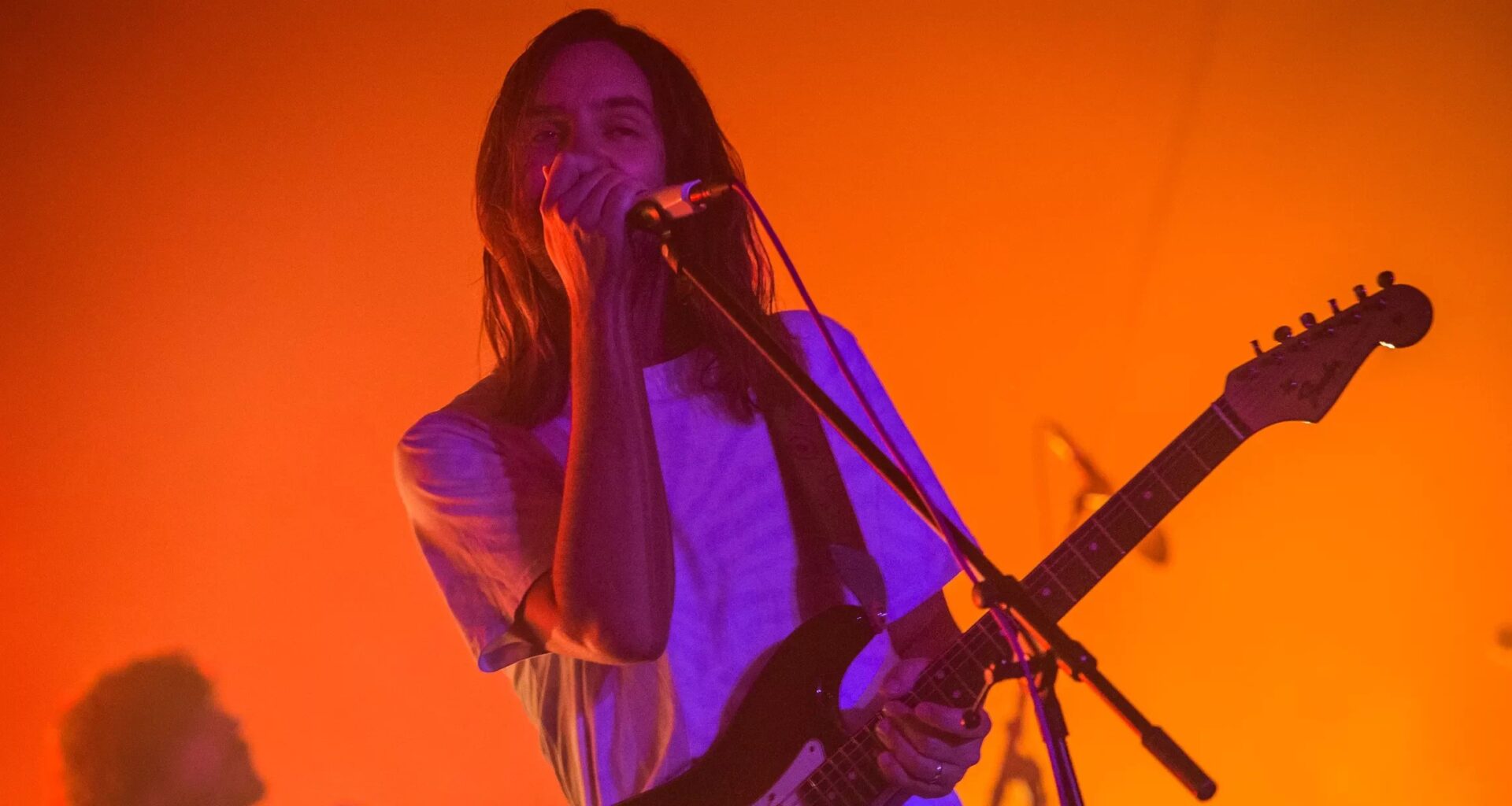 A man singing on stage under orange lights
