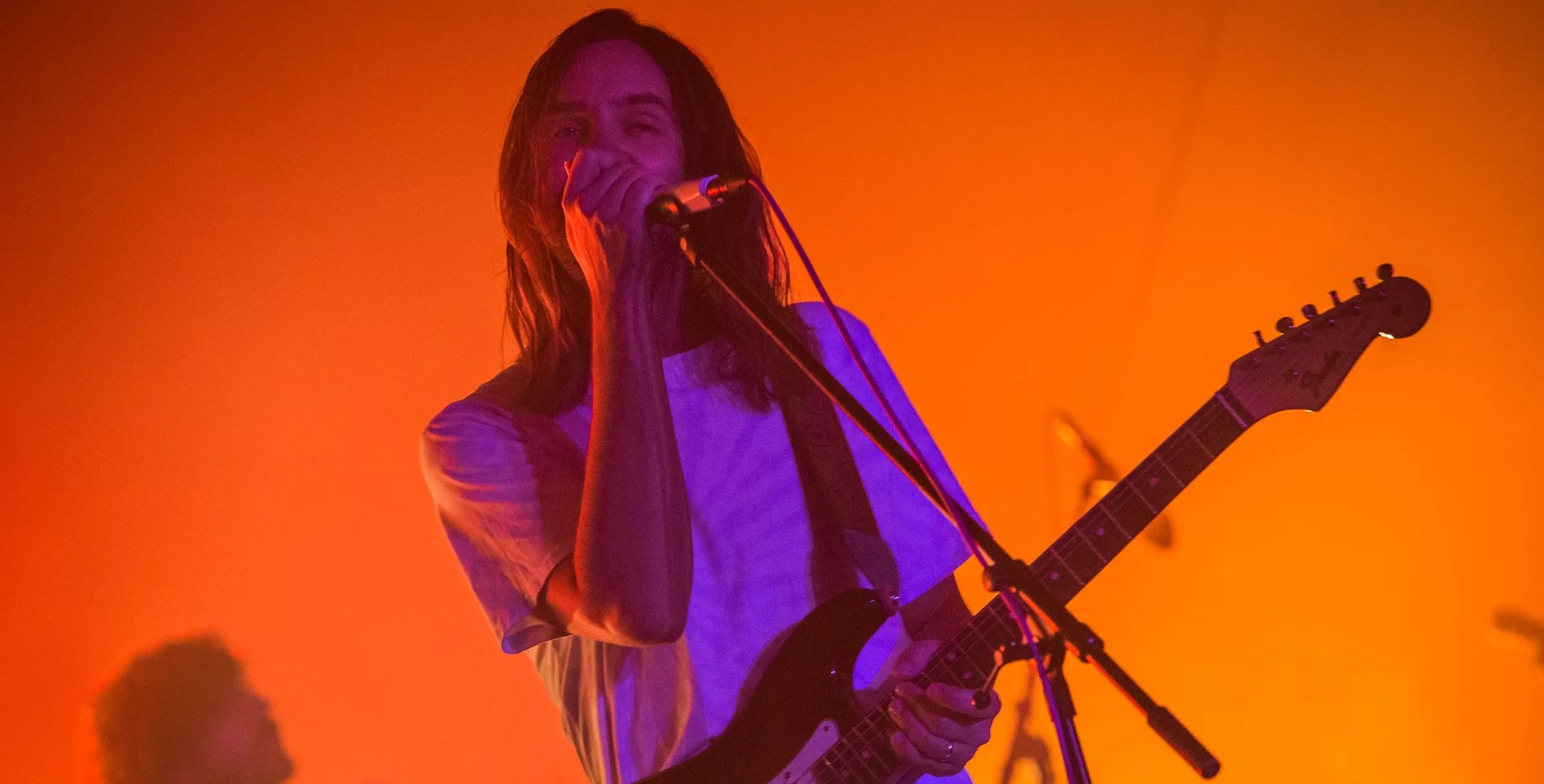 A man singing on stage under orange lights