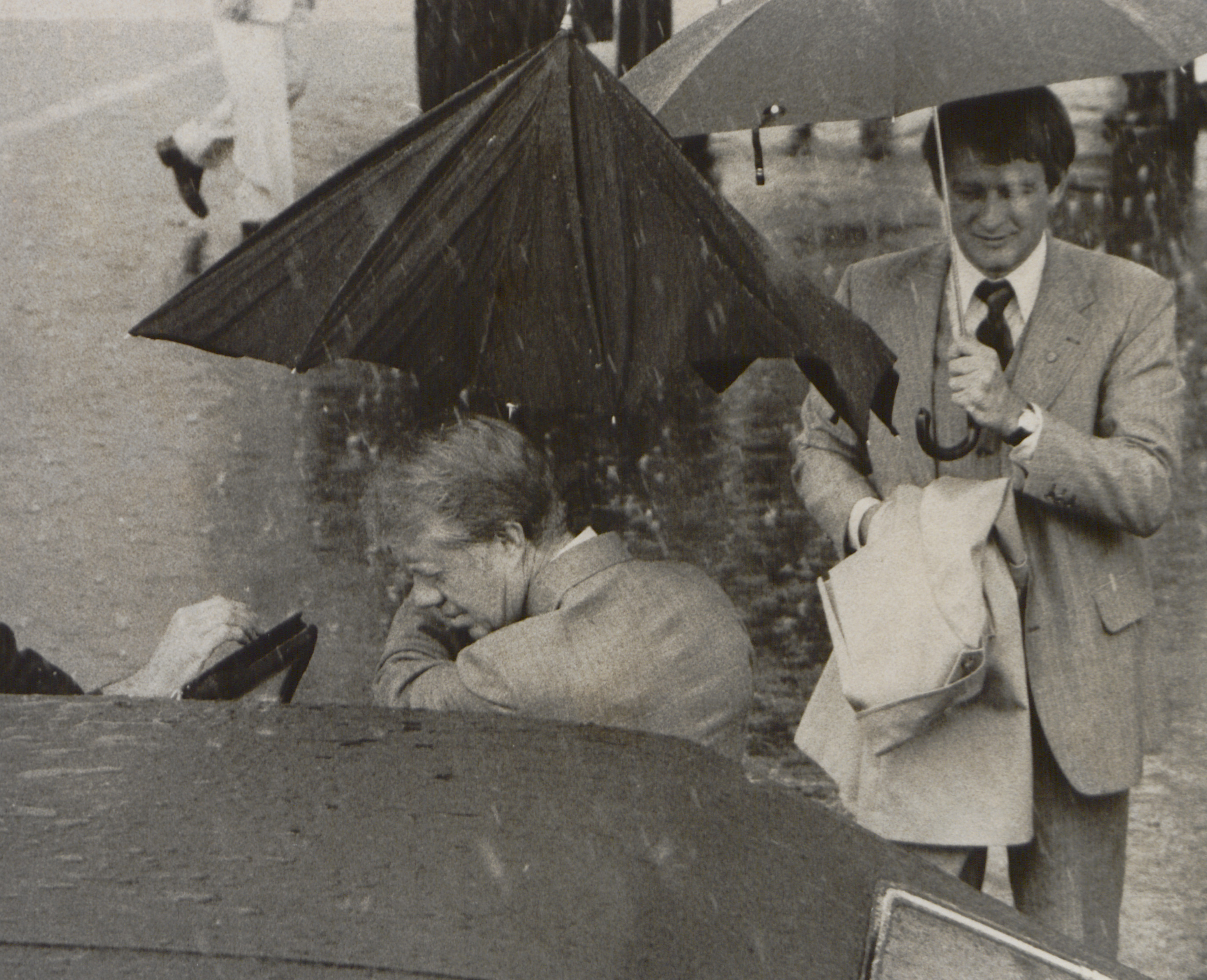 U.S. President Jimmy Carter folds an umbrella before getting inside...
