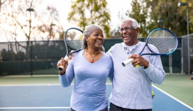 Laughing couple holding tennis rackets.