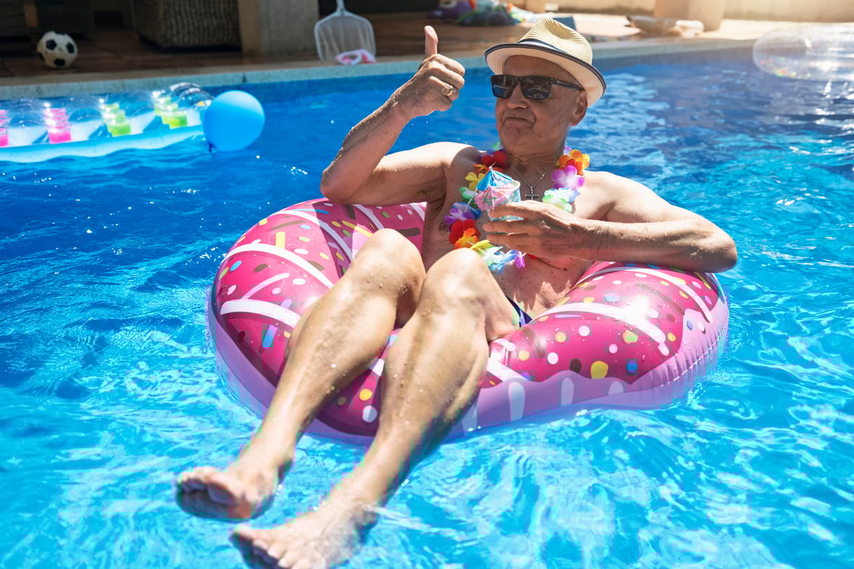 An older person in a floatation device in a swimming pool.