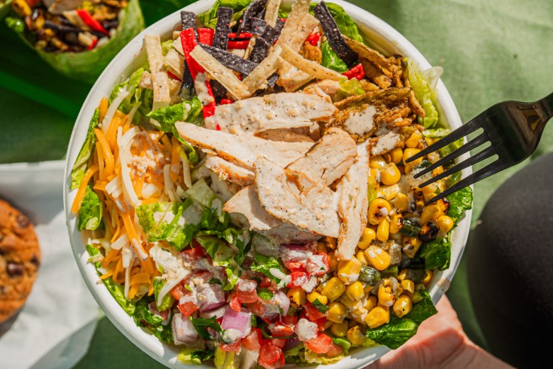 A close-up view of a fresh, colorful Southwest-style grilled chicken salad bowl from Greenlane outdoors in bright sunlight.