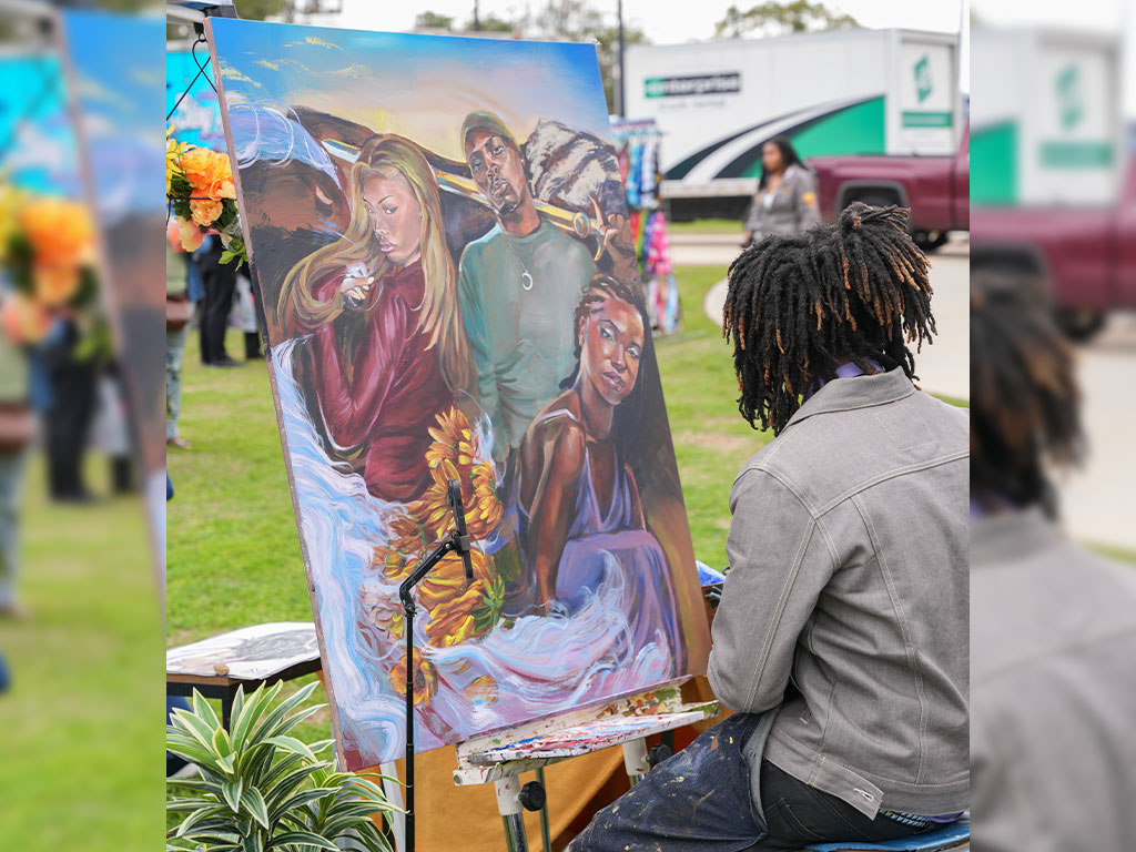 A FAMU student artist brings a vibrant portrait to life during the Harambee Festival at the Will Packer Amphitheater, capturing culture, creativity and expression in real time.