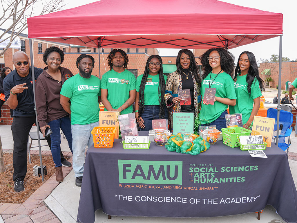 Representatives from Florida A&M University’s College of Social Sciences, Arts and Humanities engage festivalgoers during the Harambee Festival, showcasing academic programs and community impact at their interactive booth.