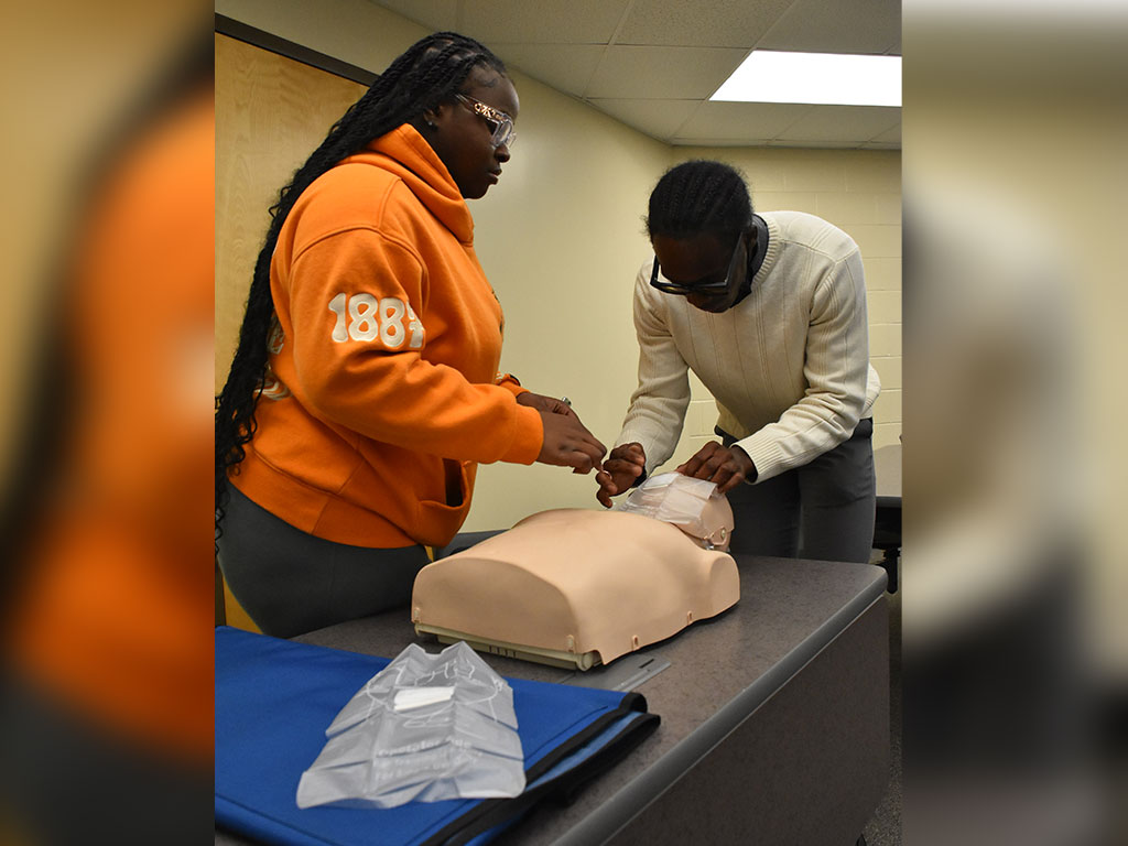 Students at Florida A&M University practice life-saving CPR techniques on a training mannequin during a Black Men in Medicine certification event on campus.