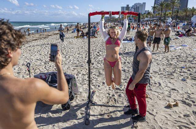 Carlee Fitch, 18, a student from the University of Florida, tries to do a pull-up while visiting Las Olas Beach during spring break on Friday, March 20, 2026, in Fort Lauderdale, Fla.