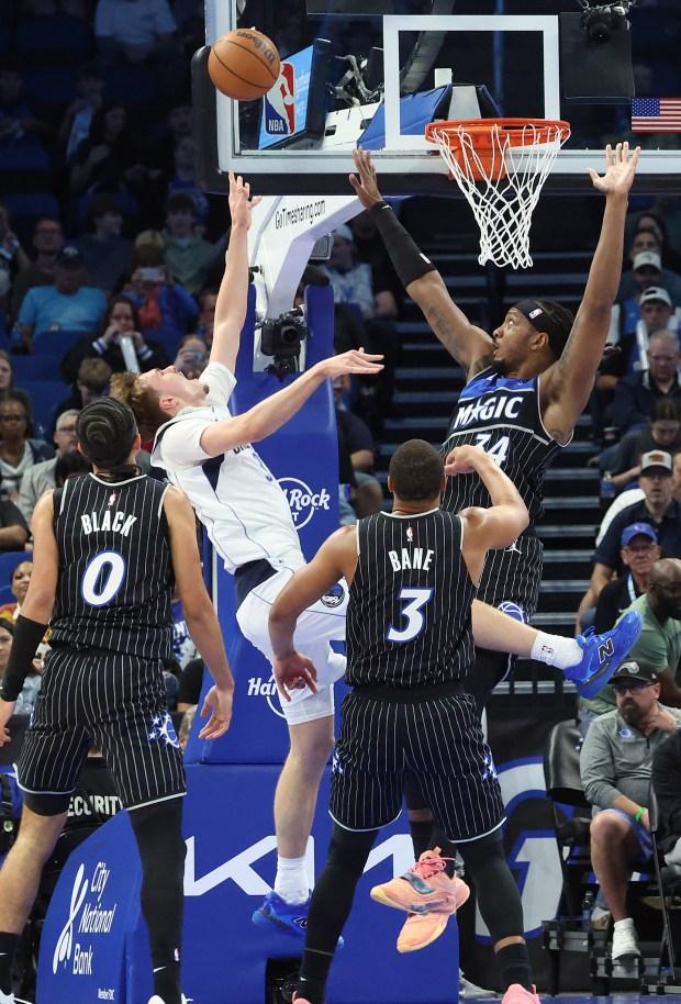 Dallas guard Cooper Flagg (white jersey) falls as he shoots among Orlando defenders during the Dallas Mavericks at Orlando Magic NBA game at the Kia Center on Thursday, March 5, 2026. (Stephen M. Dowell/Orlando Sentinel)