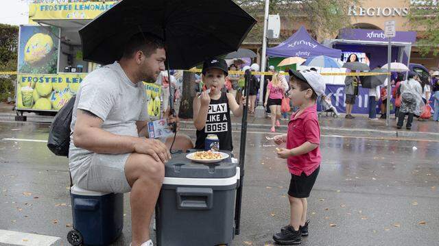 Alejandro Galindo, of Cuba origin, enjoys French Fries with his sons Ethan and Dylan in the middle of SW 8th street during Calle Ocho festival on Sunday, March 15, 2026 in Little Havana. Andrew Uloza / for Miami Herald