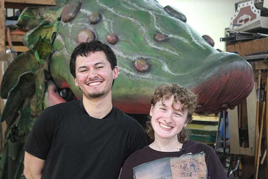 Audrey II puppeteer Noah Garcia poses in scene shop with Prop Master Laura Lupita.