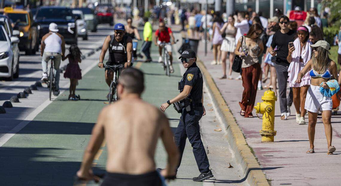 A Miami Beach police officer looks on as people make their way down Ocean Drive during spring break on Saturday, March 21, 2026, in Miami Beach, Florida.