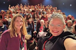 Festival co-chairs Roxana Levin and Anat Mansour pose in front of a packed theatre.