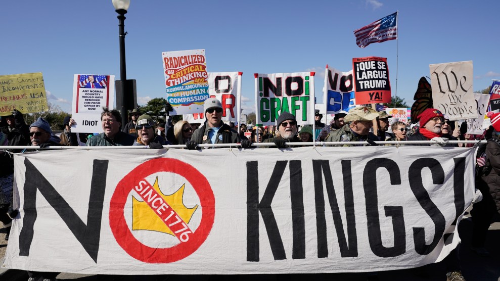Protestors walk with a large No Kings sign. An American flag is seen in the background.